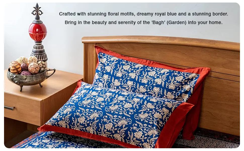 A bed made up in the blue floral bedsheet and pillow covers with a red border