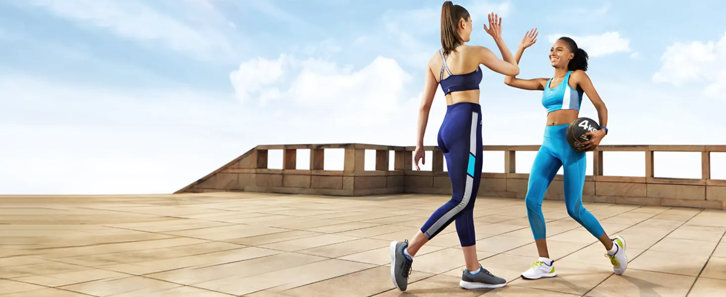 Two women in activewear giving each other a high five