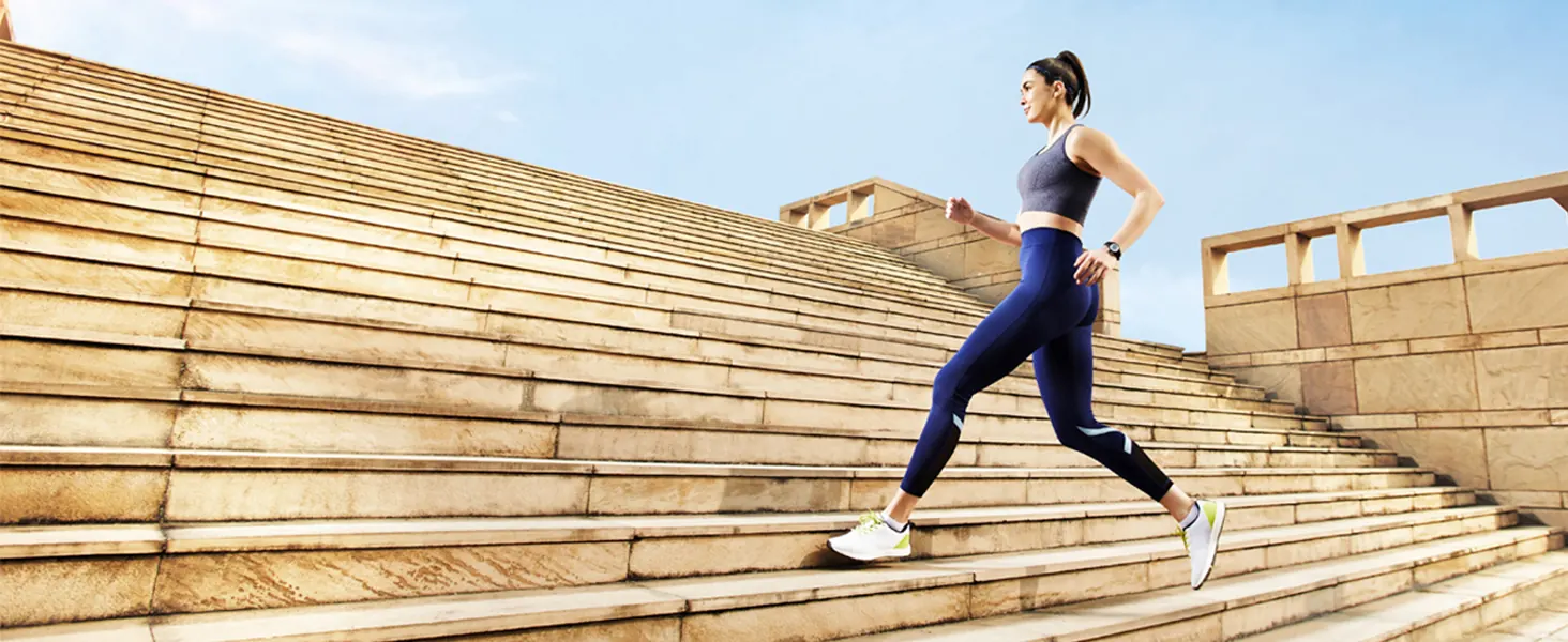 A woman running up stone steps in the sun