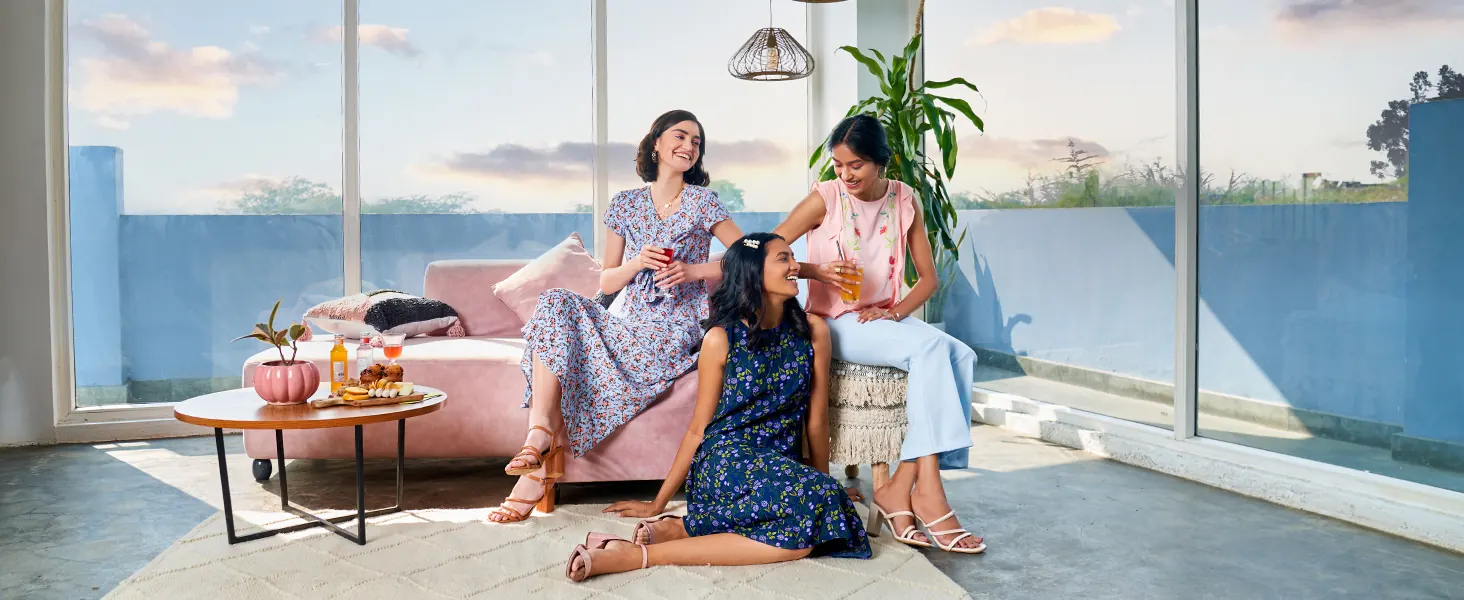 Three women on a pink sofa by a window