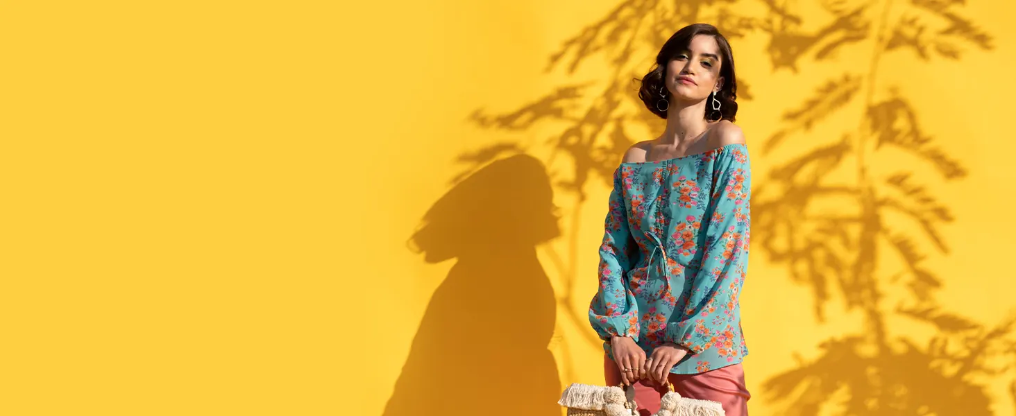 A woman in a blue floral top against a yellow wall