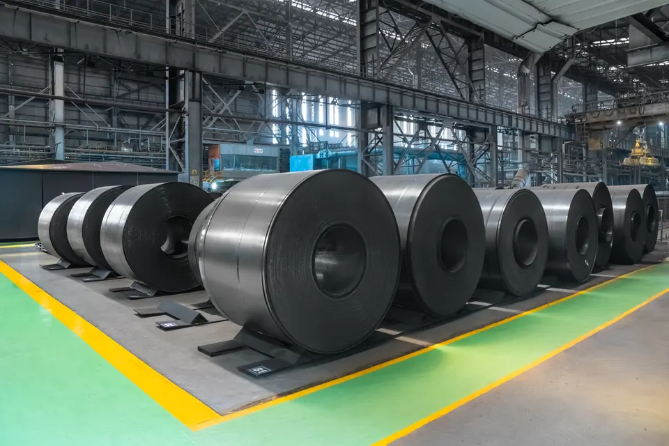 Rows of black steel coils on a floor marked in green and yellow