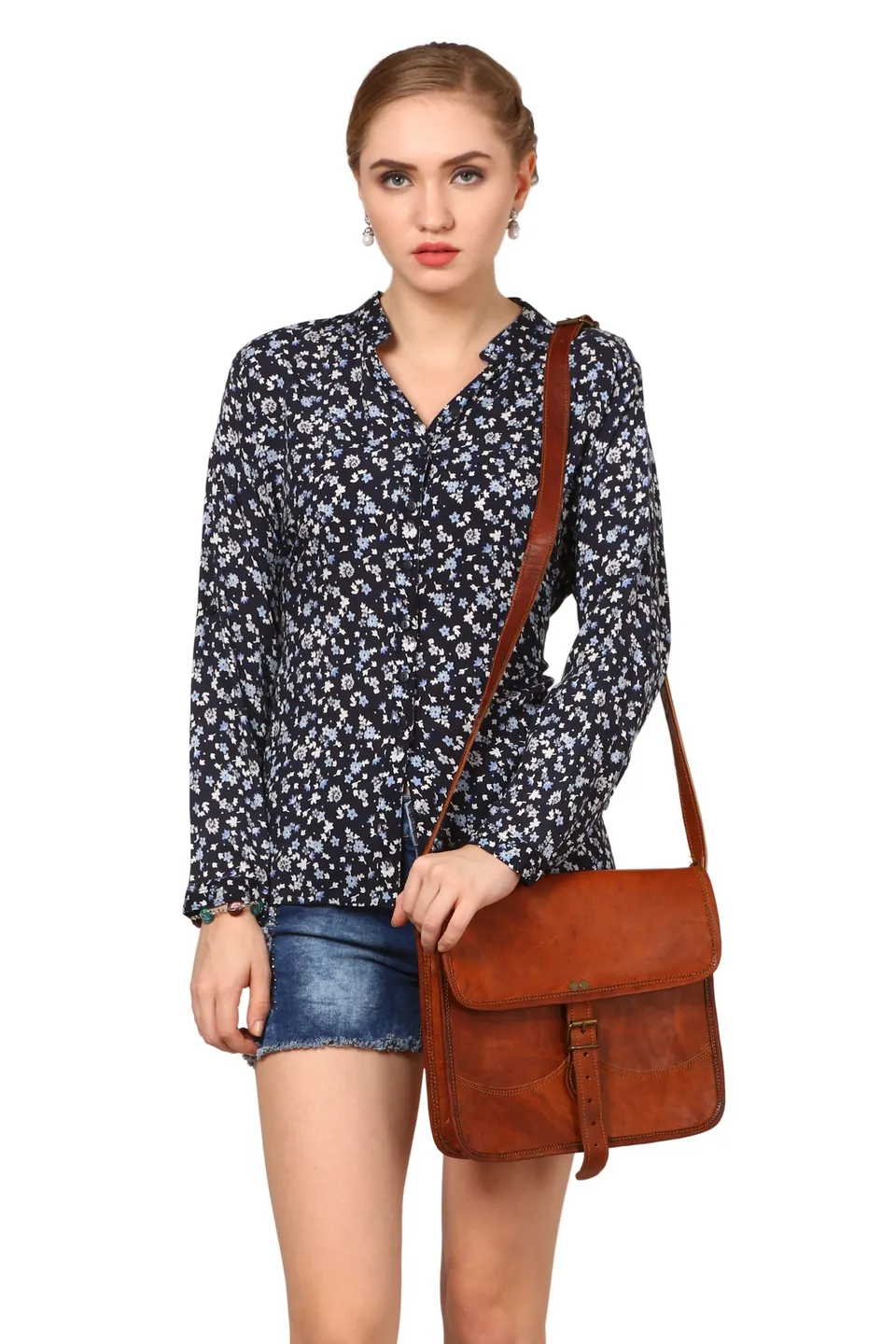 A model in a navy floral shirt carrying a brown leather messenger bag, on white