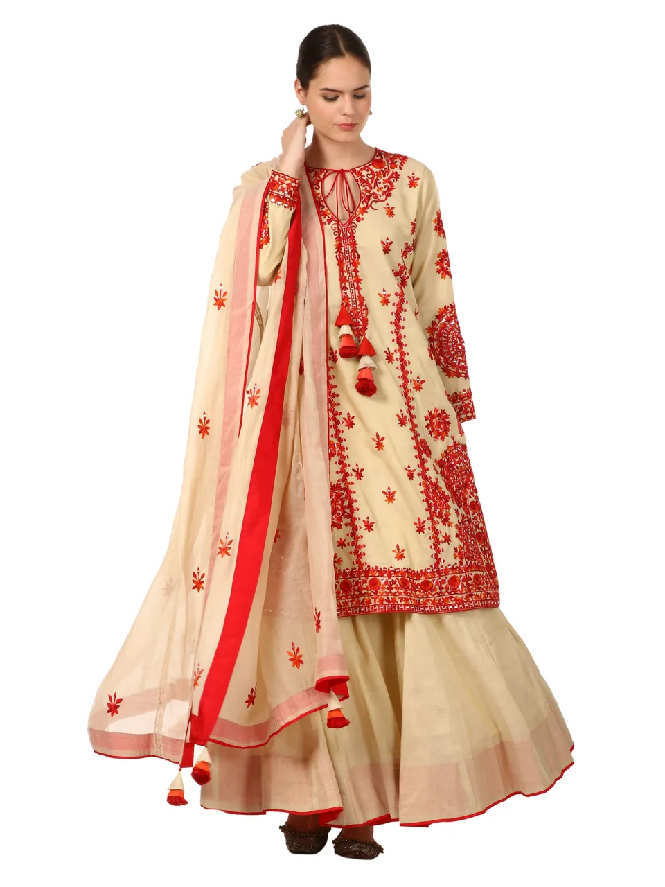 A model in a cream kurta with red embroidery and a flared skirt, holding out a red-bordered dupatta, on white