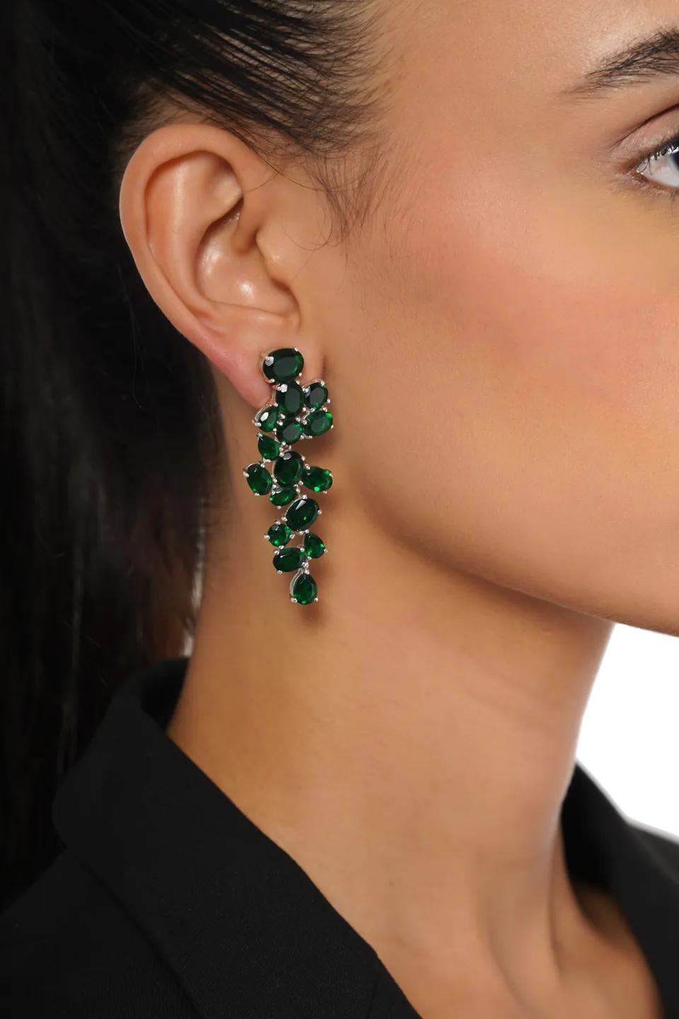 Close-up of a green crystal cluster earring on a model’s ear