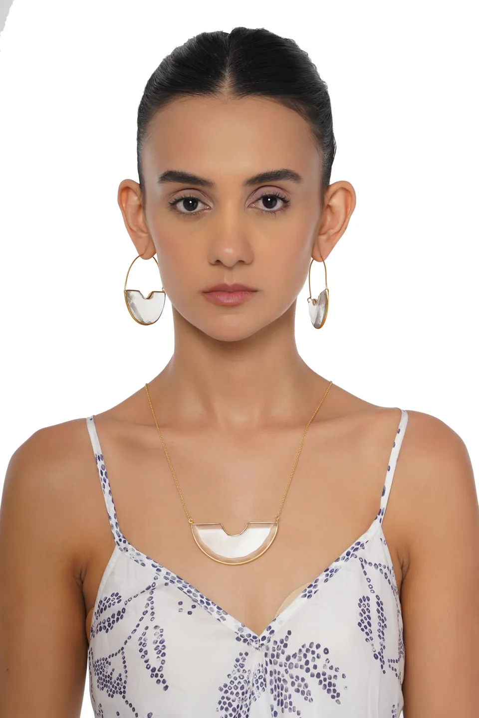 A model wearing large hoop earrings with clear crescents and a matching pendant