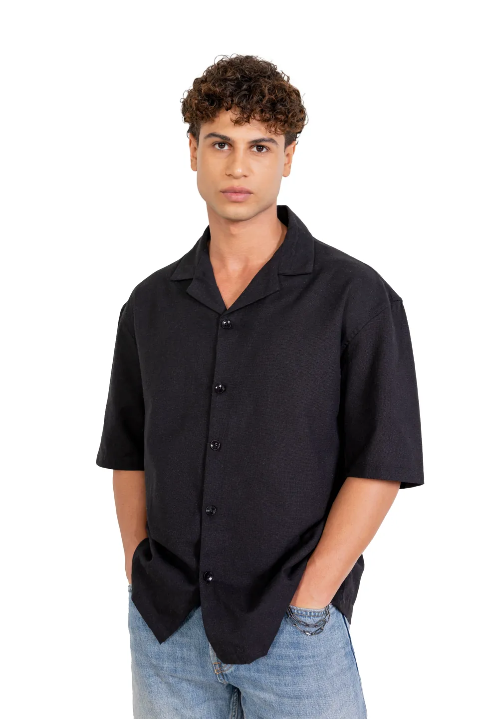A male model in a black short-sleeved shirt and blue jeans, on white