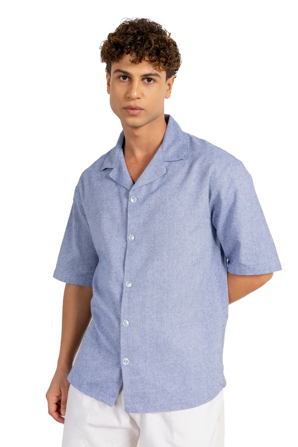 A male model in a light blue short-sleeved shirt and white trousers, on white