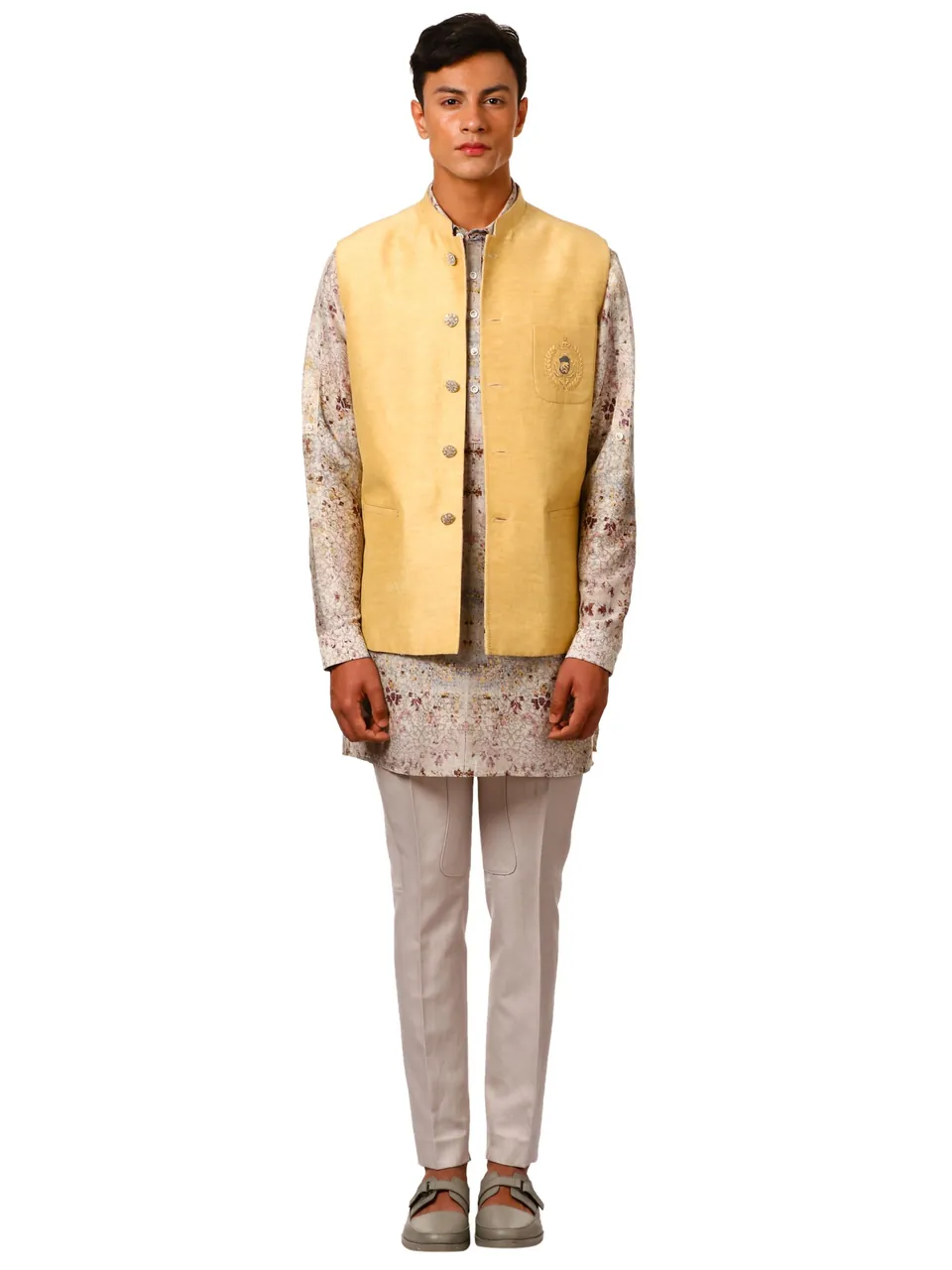 A male model in a yellow Nehru jacket over a printed kurta, on white