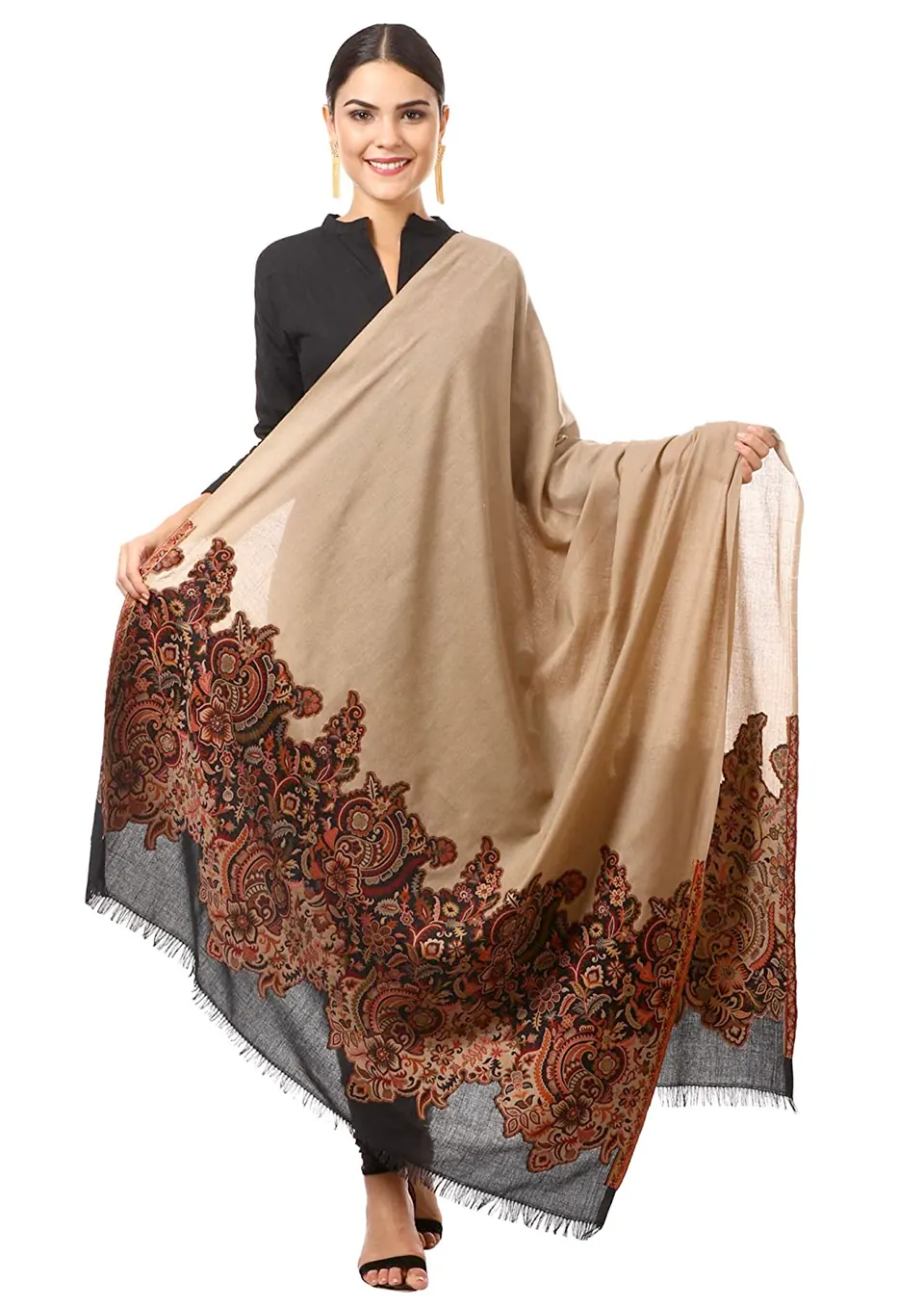 A female model holding open a beige wool shawl with a paisley border, on white