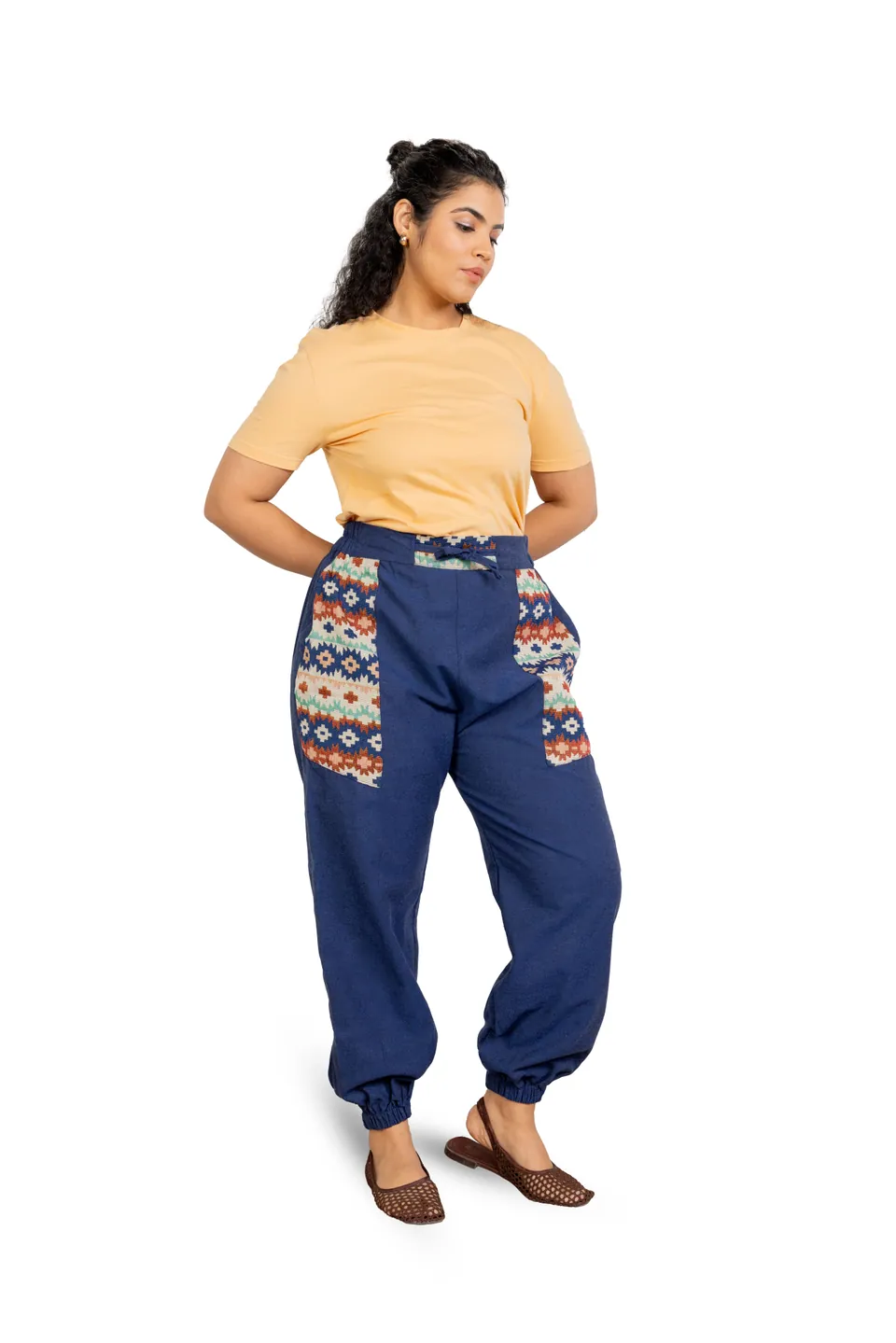 A model in a yellow T-shirt and blue joggers with printed pockets, on white